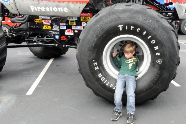 boy fitting inside a monster truck wheel