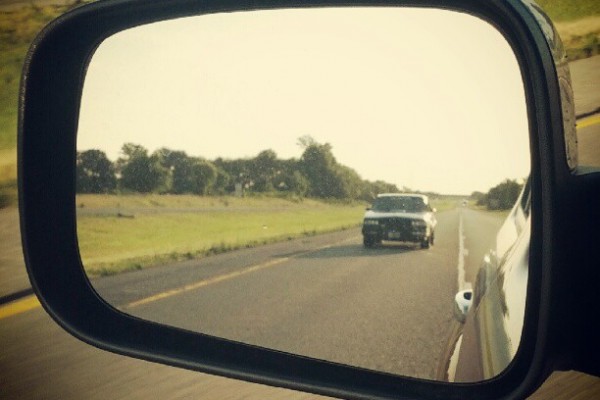 buick grand national in a side mirror on highway