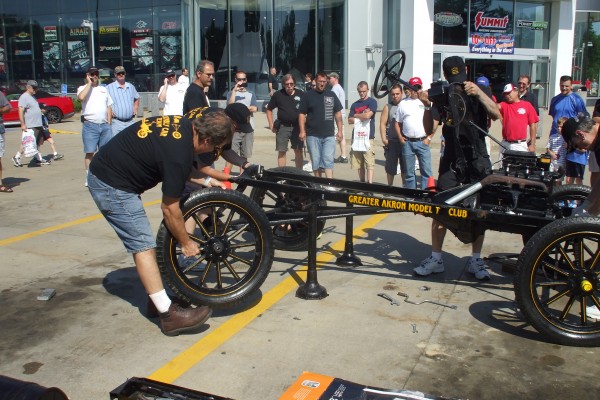 men assembling a ford model t demonstration, fitting wheels