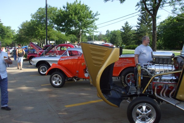 row of classic dragsters at a car show