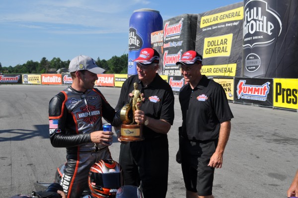pro stock motorcycle rider being handed wally trophy