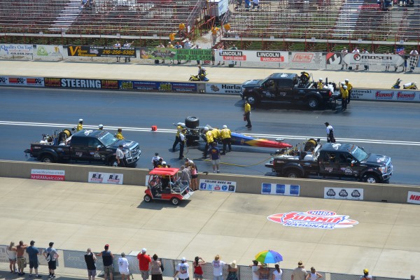 crews cleaning a dragster from the track after a crash