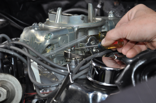 person adjusting carburetor throttle linkage