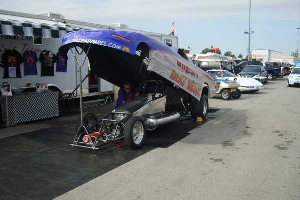 nhra funny car with body lifted up in pits