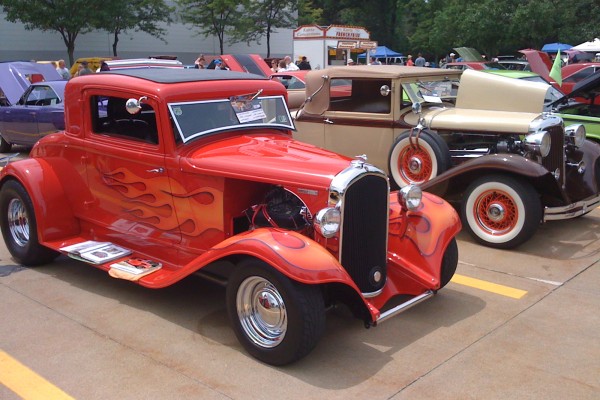 a pair of vintage plymouth prewar hot rods at a car show