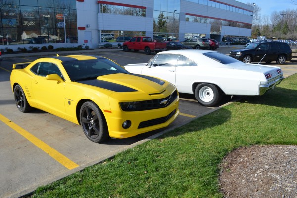 a 5th gen camaro and 1965 impala in a pakring lot