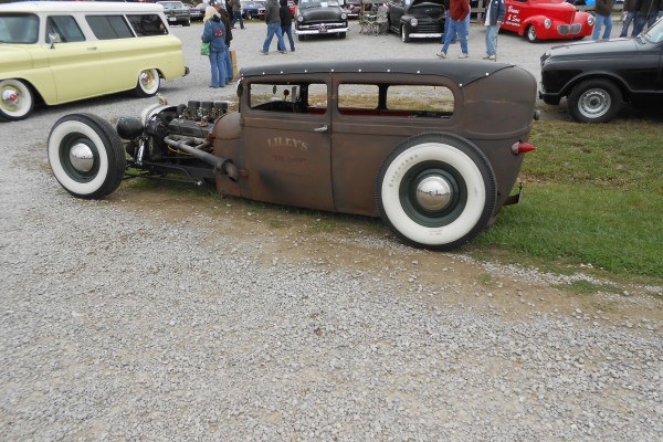rear side view of a rat rod tudor coupe at a car show