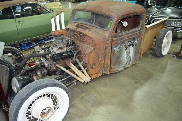 rusty rat rod pickup truck at indoor car show