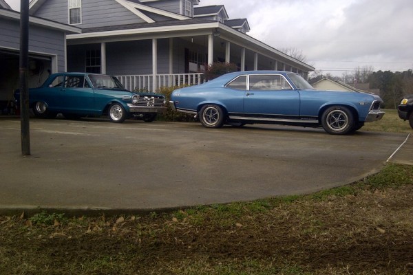 a pair of chevy nova cars in a driveway