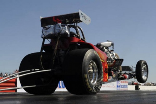 vintage dragster doing a wheelstand at dragstrip