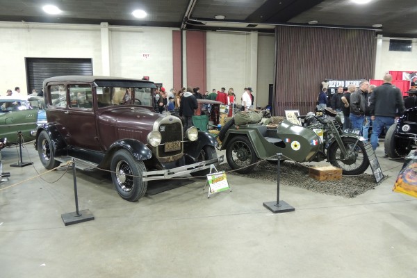 vintage cars and motorcycles at an indoor hot rod display