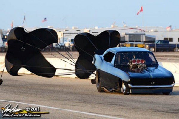 funny car with parachutes deployed at end of a drag race