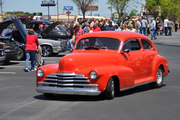 red hotrod driving into car show