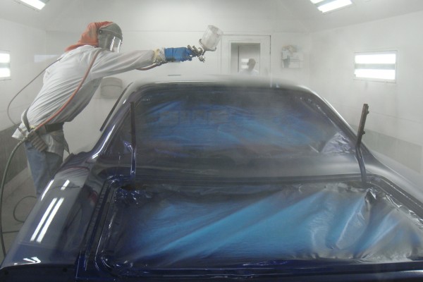 spraying paint on a dodge super bee in booth