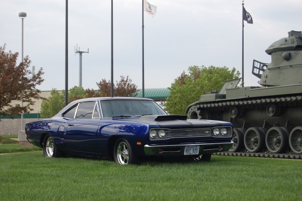 vintage dodge super bee displayed near an army tank