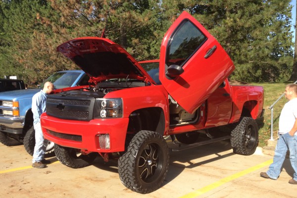 Lifted red Chevy pickup with Lambo doors