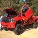 Lifted red Chevy pickup with Lambo doors thumbnail