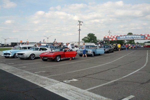 classic cars lining up in staging lanes of a race track