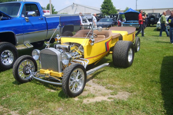 a yellow t bucket ford hot rod pulling a matching trailer