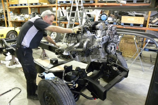 man lowering ls3 engine onto a hot rod frame