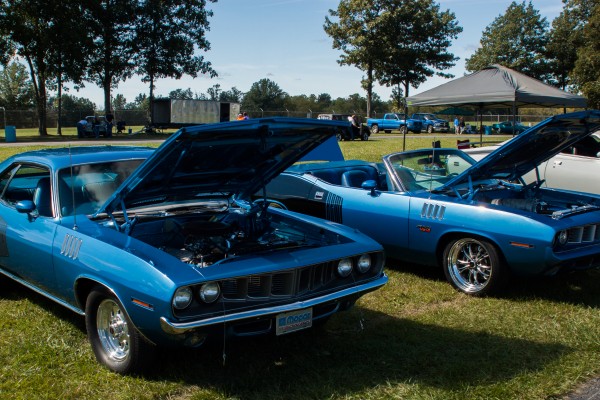 a pair of 1971 plymouth barracuda muscle cars at a car show