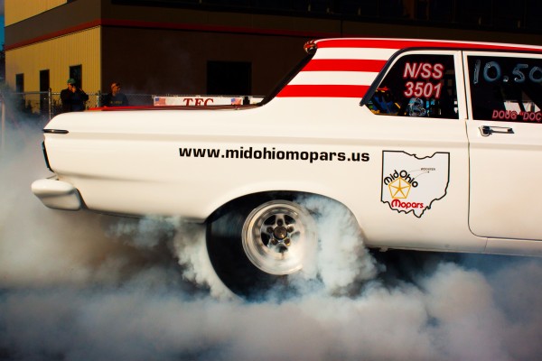 rear end view of a mopar muscle car doing burnout at drag strip
