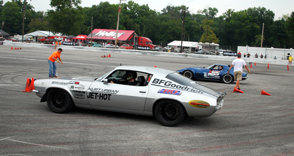 a vintage camaro and corvette stingray racing on autocross course