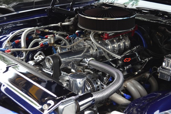 supercharged v8 engine under the hood of a vintage camaro