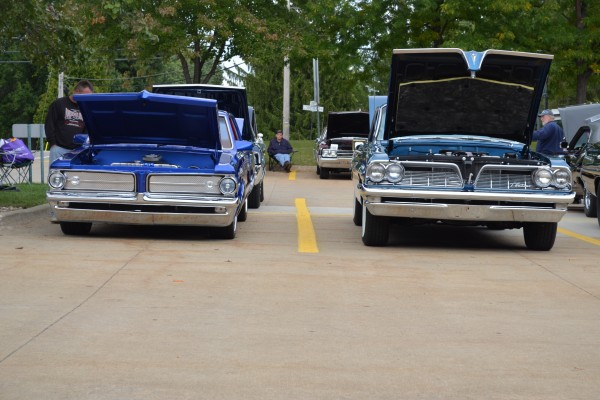 a pair of vintage pontiac coupes from the 1960s at a car show