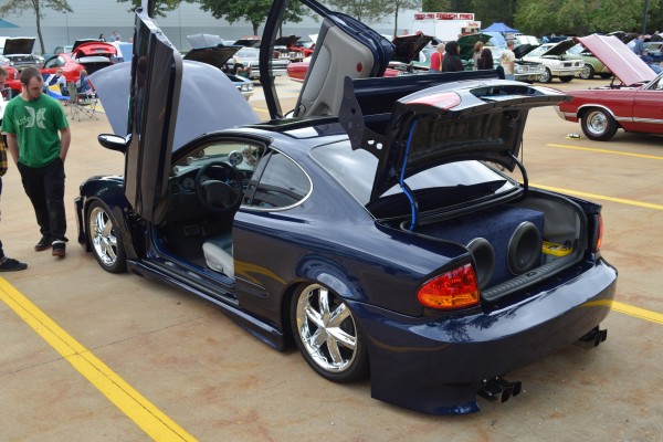 customized olds alero with scissor doors at a car show