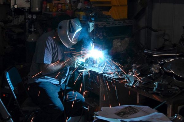 artist welding sculpture on a table