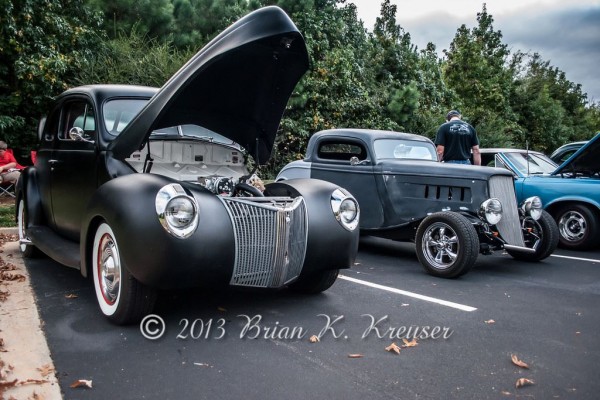 a row of classic hot rods at a car show