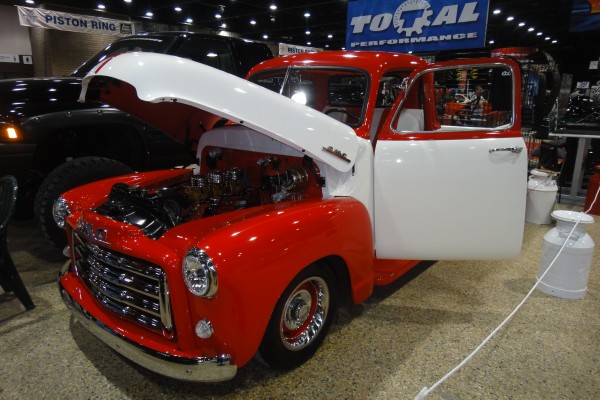 red and white vintage gmc pickup truck at a car show