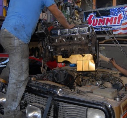 man putting an engine in an old truck