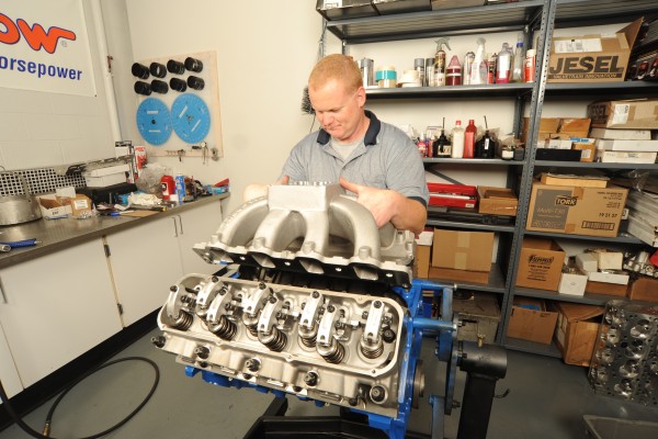 man fitting an intake manifold onto a v8 engine