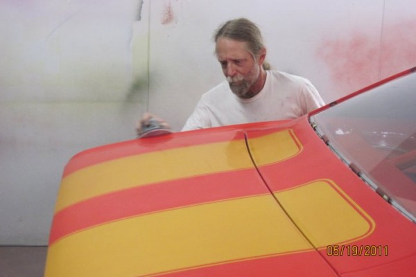man sanding paint on a vintage Camaro fender and trunk lid