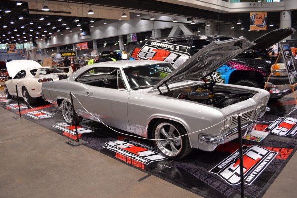 silver 1960s chevy impala custom lowrider on display at indoor car show