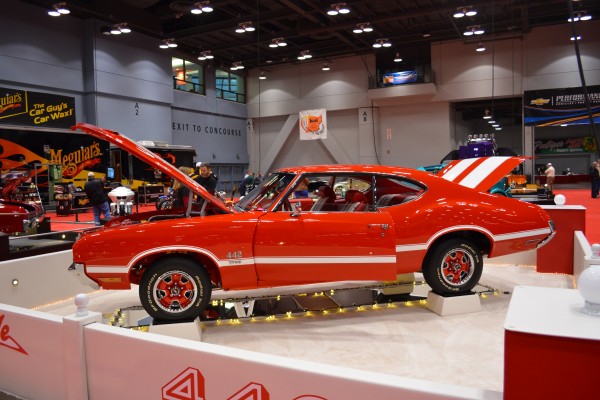 orange and white Oldsmobile cutlass 442 displayed at indoor car show