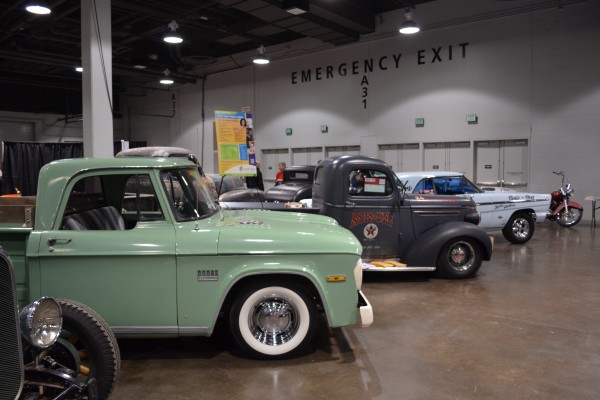 row of classic cars and trucks displayed at indoor car show