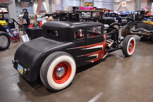a ford five window hot rod coupe displayed at indoor car show