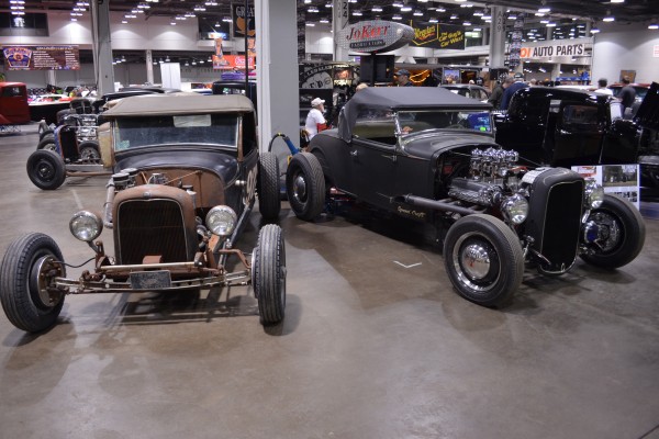 a pair of ford prewar hot rod roadsters displayed at indoor car show