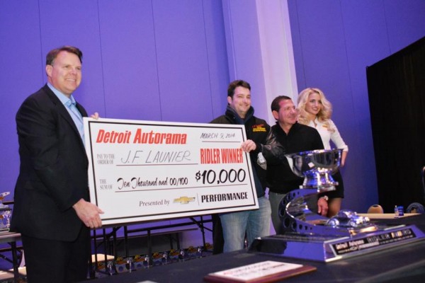 man awarding oversized on display at indoor car show prize check to a car show winner