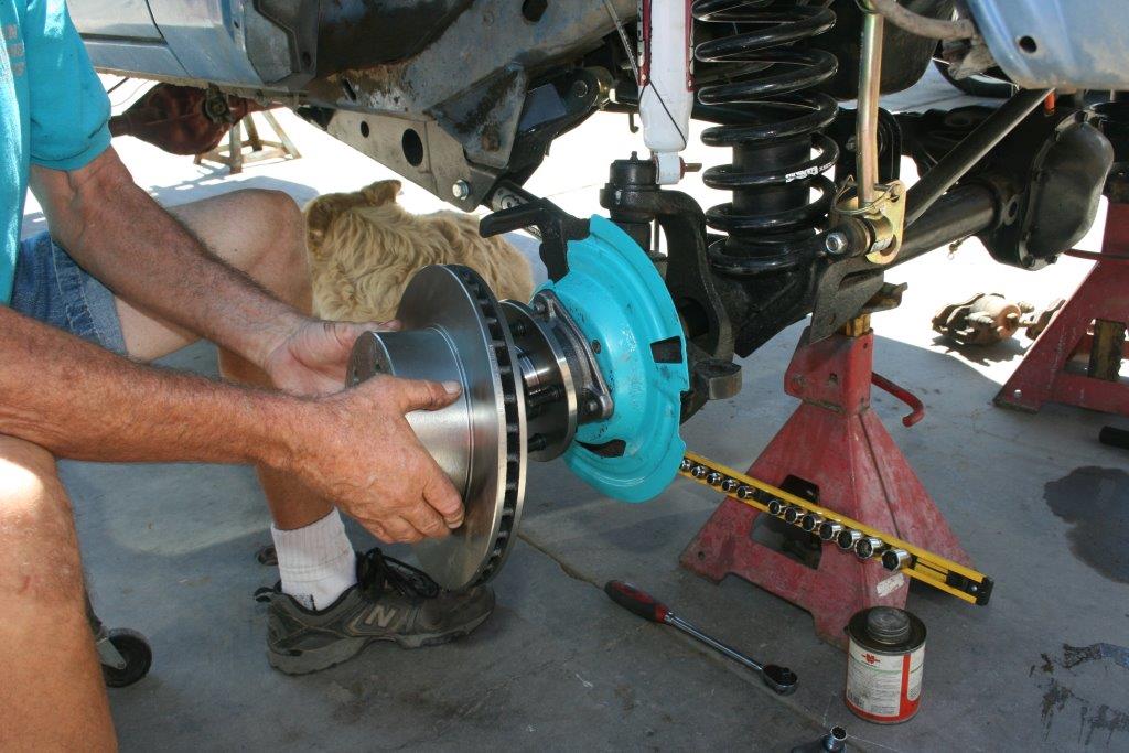 man fitting brake rotor onto a jeep cherokee hub