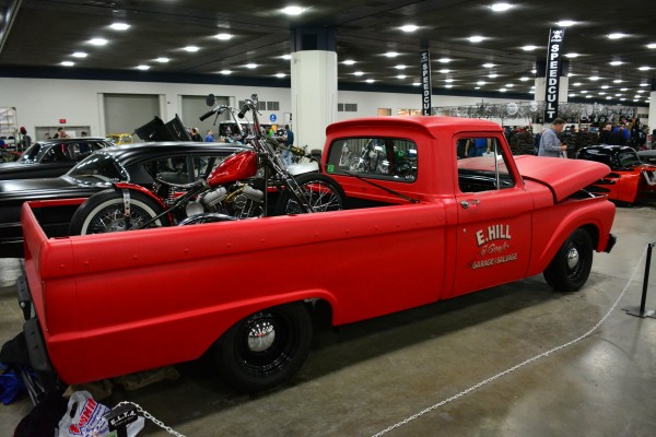 vintage truck with a custom motorcycle in the bed at indoor car show