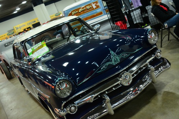 a pinstriped postwar hotrod coupe on display at indoor car show