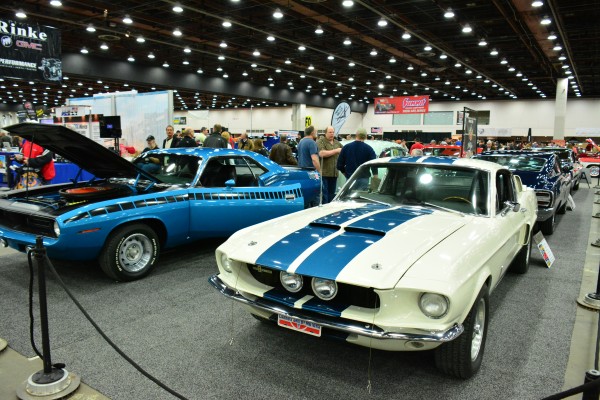 a vintage mustang and barracuda on display at indoor car show