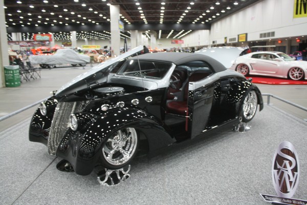 custom black hot rod roadster on display at indoor car show