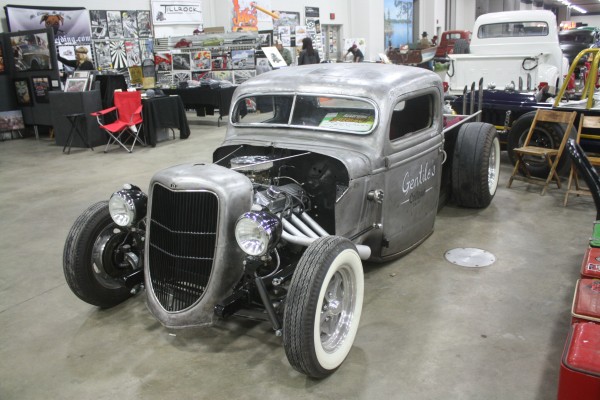 vintage ford hot rod truck in bare metal on display at indoor car show