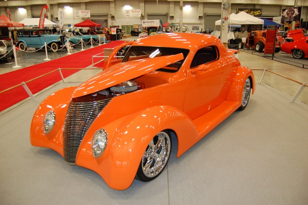 orange hot rod custom coupe on display at indoor car show