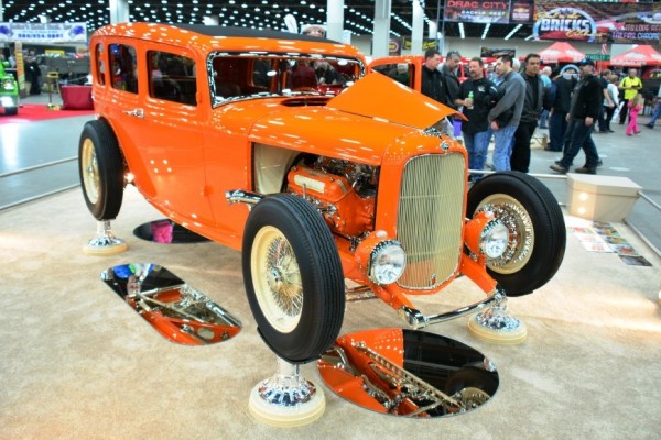 orange ford hot rod sedan on display at indoor car show